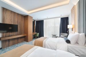 a hotel room with two beds and a flat screen tv at Bristol Hotel Podgorica in Podgorica