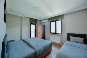 a bedroom with two beds and two windows at EMİSSA MOTEL in Akçatepe