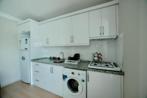 cocina con armarios blancos, lavadora y secadora en EMİSSA MOTEL, en Akçatepe