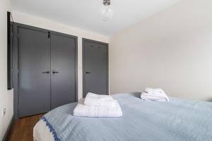 ein weißes Schlafzimmer mit einem Bett mit Handtüchern darauf in der Unterkunft Central 1 BD + Sofa Bed in the Heart of Cheltenham! in Cheltenham