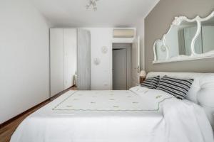 a white bedroom with a white bed and a mirror at A casa di Mo', a due passi dalla Stazione e Fiera in Bologna