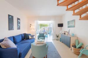 uma sala de estar com um sofá azul e cadeiras em La Pélagie - Maison climatisée vue mer em Sainte-Maxime