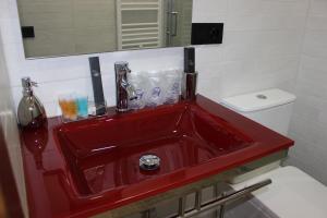 a red sink in a bathroom with a toilet at SUITE DEL CASTILLO in Andújar