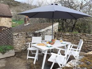 une table et des chaises blanches avec un parasol dans l'établissement Maison rénovée sur domaine viticole Renovated old house on wine estate, à Chassey-le-Camp
