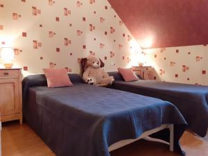 a teddy bear sitting on two beds in a room at Maison rénovée sur domaine viticole Renovated old house on wine estate in Chassey-le-Camp