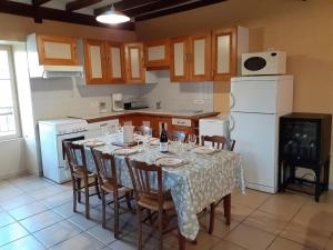 een keuken met een tafel met stoelen en een witte koelkast bij Maison rénovée sur domaine viticole Renovated old house on wine estate in Chassey-le-Camp