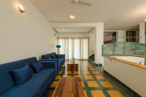 a living room with a blue couch and a pool table at Villa 9C by Revkeys in Bangalore