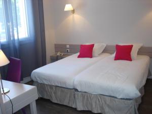 a hotel room with two beds with red pillows at Hotel-Restaurant Du Lac in Joue-les-Tours