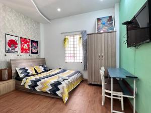 Schlafzimmer mit einem Bett, einem Schreibtisch und einem TV in der Unterkunft SAkURA Private Room 201 -Cheap-Saigon in Ho-Chi-Minh-Stadt
