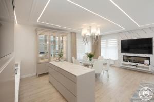 a white kitchen and dining room with a table at Nadmorskie Tarasy - Apartments M&M in Kołobrzeg