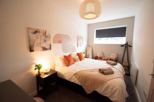 Schlafzimmer mit einem Bett mit weißer Bettwäsche und orangefarbenen Kissen in der Unterkunft Ideal Lodgings in Walkden 