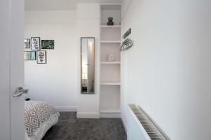 a white room with a mirror and a bed at Cowdray Avenue in Colchester