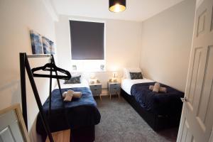 a small bedroom with two beds and a window at Ideal Lodgings in Walkden 