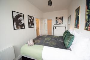 a bedroom with a bed and some pictures on the wall at Ideal Lodgings in Walkden 