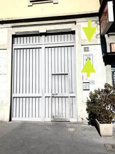 a white garage door with a green arrow on it at Domus Vacanza in Milan