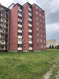 a red building with a grassy field in front of it at Nikea 51 Apartment in Kutaisi
