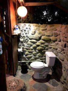 a stone bathroom with a toilet and a stone wall at Ocean View rustic cabin in the jungle by the surf in Pavones