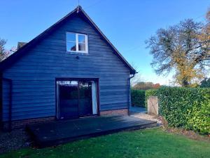 una casa azul con una rampa que conduce a un garaje en Converted Countryside Barn, en Inkpen