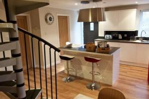 a kitchen with a counter and two stools at Converted Countryside Barn in Inkpen