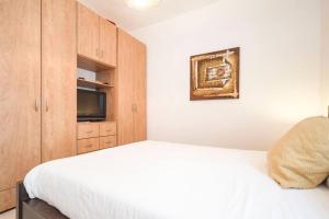 1 dormitorio con 1 cama blanca y TV en Lovely 2 rooms with big terrace en Tel Aviv