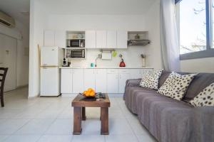 sala de estar con sofá, mesa y cocina en Lovely 2 rooms with big terrace en Tel Aviv