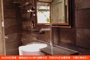 a bathroom with a sink and a mirror and a toilet at Spring BnB in Kenting