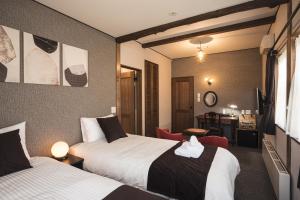 a hotel room with two beds and a desk at Shinkyo Inn in Nikko