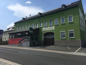 un bâtiment vert sur le côté d'une rue dans l'établissement Gasthof „Zum Schwan“, à Langenbach