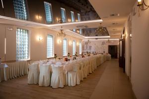 a row of tables with white chairs in a room at Hotel Carskie Koszary in Zamość