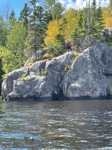Larouche的住宿－Les Chalets Baie Cascouia, Nature & Expérience，站在水边的岩石上的人