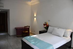 a bedroom with a white bed and a chair at Raffin Royal Lodge 