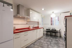 una cocina con armarios blancos y una mesa con sillas. en Ibirriaga - baskeyrentals en Mutriku