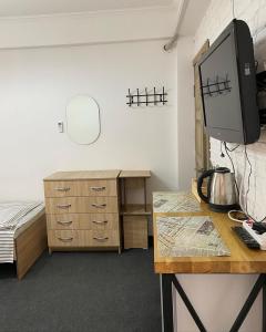 a room with a bed and a desk with a television at Zaton Guesthouse in Cholpon-Ata