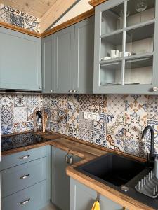 a kitchen with blue cabinets and tiles on the wall at Vila Liberta in Poprad