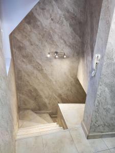 y baño con ducha y pared de piedra. en Apart Centar, en Plovdiv