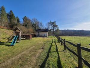 un parque infantil en un campo con una valla de madera en Lovely holiday home in Orval with garden en Florenville