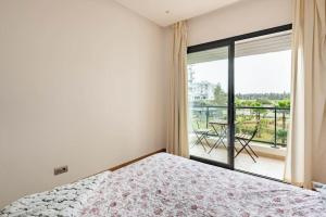 a bedroom with a bed and a balcony with a table at Lovely Appartement Prestigia Hayriad in Rabat