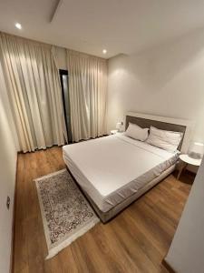 1 dormitorio con 1 cama blanca grande y suelo de madera en Lovely Appartement Prestigia Hayriad en Rabat
