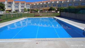 a large blue swimming pool in front of a building at CHALET CON PISCINA EN MIÑO-Perbes in Miño