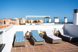 un patio con sillas y mesas en la azotea en Sunny Luxury Apartment with two-level terrace, two swimming pools, next to golf course, en Caleta de Fuste