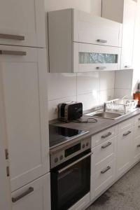 una cucina con mobili bianchi e un forno a piano cottura di MK Apartments Delmenhorst nähe Bremen 12 a Delmenhorst