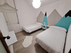 een kleine kamer met 2 bedden en een kroonluchter bij Ribeira Sacra Apartament in Monforte de Lemos