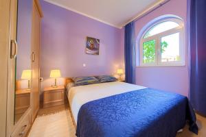 a purple bedroom with a bed and a window at Apartments Mira in Porat