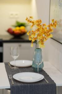 stół z dwoma kieliszkami i wazon z żółtymi kwiatami w obiekcie Niemcewicza Pet-Friendly Apartment by Renters w Warszawie