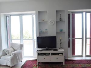 a living room with a tv and a chair and windows at Seaview lovely Villa in Leonidio
