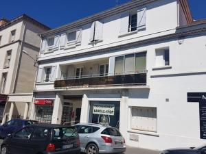 Appartement T3 confortable à Royan, proche plage et commerces - FR-1-71-51 في رويان: مبنى أبيض مع سيارات متوقفة أمامه