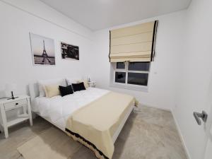 a white bedroom with a large bed and a window at VINNA Просторі апартаменти в новобудові. in Ternopil