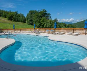 a large swimming pool with blue umbrellas and chairs at White Mountain Vista! in Lincoln