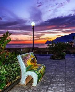 a bench sitting next to a light pole with a sunset at Torrevarata vacanze in Santa Teresa di Riva