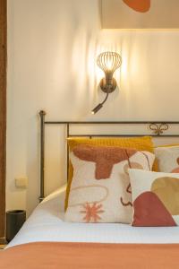 a bed with orange pillows and a light on the wall at Canalview Hotel Ter Reien in Bruges